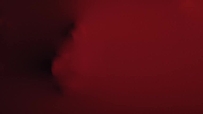 Face pressed against red surface with faintly visible facial contours