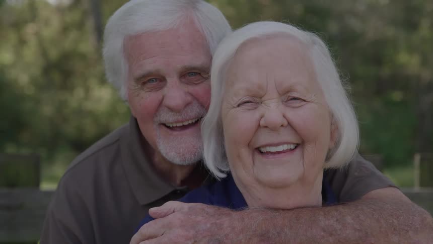 The elderly people are hugging and smiling