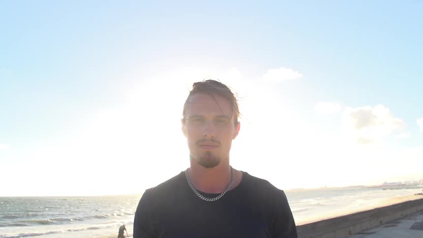 Man standing on the beach facing away from the water