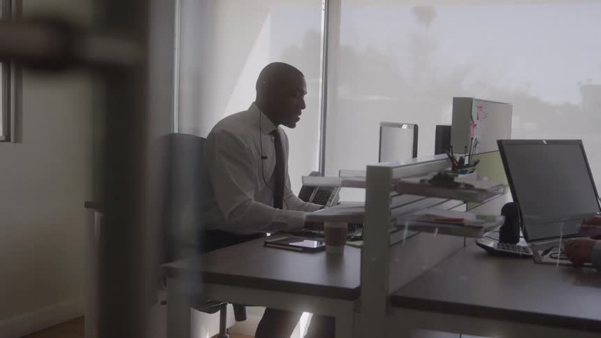 A professional businessman sits at his desk in an office while using his computer