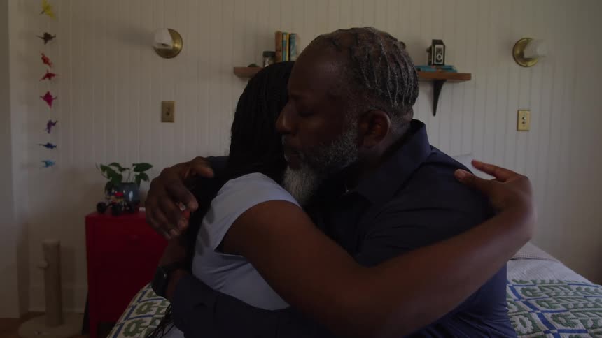 A father comforts his sad daughter with a warm hug on a bed in a bedroom