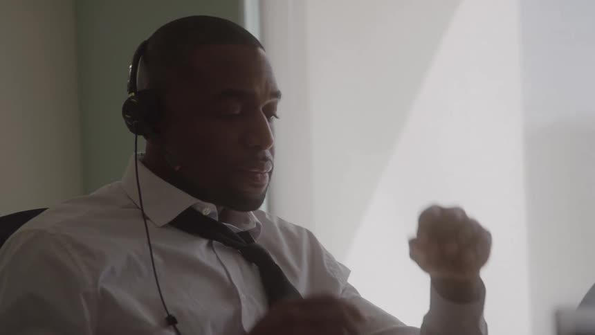 The man in the office removes his headphones