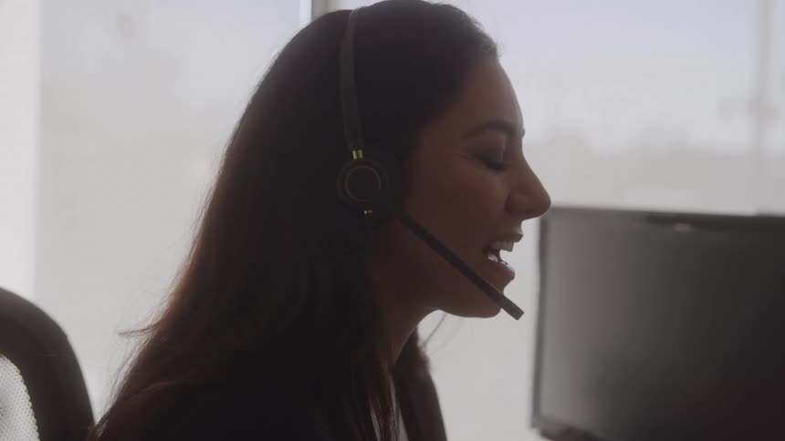 Woman sitting in an office speaks via her headset during the daytime