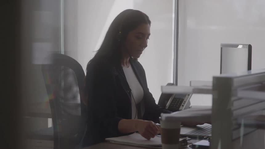 The woman is sitting at her desk in front of her computer