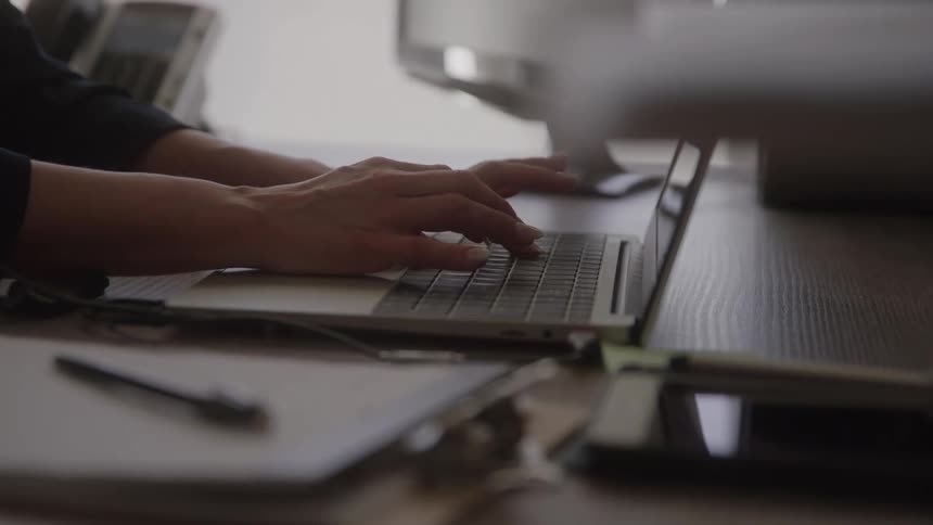 Woman types on a laptop while sitting in her office