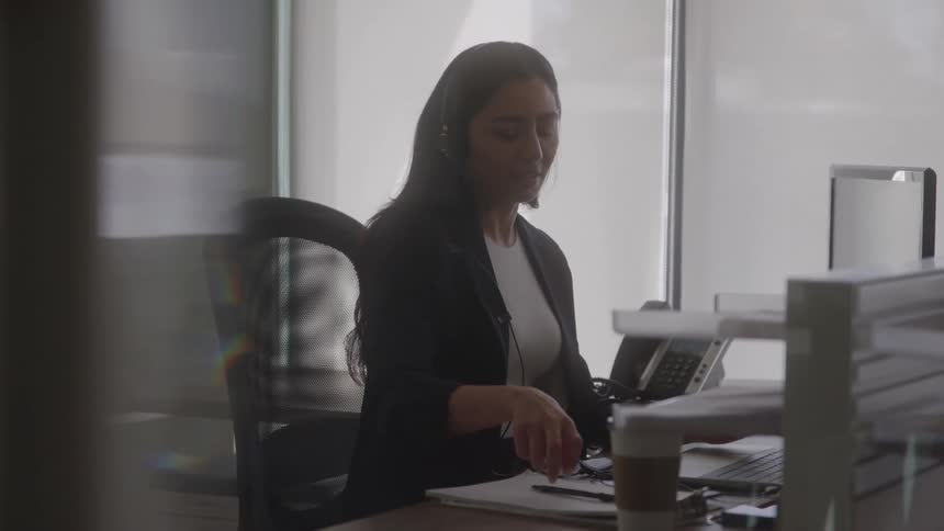 The woman takes notes at her desk