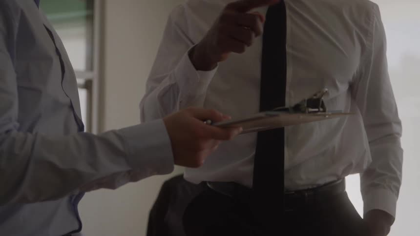 Men in suits review a clipboard during a business meeting