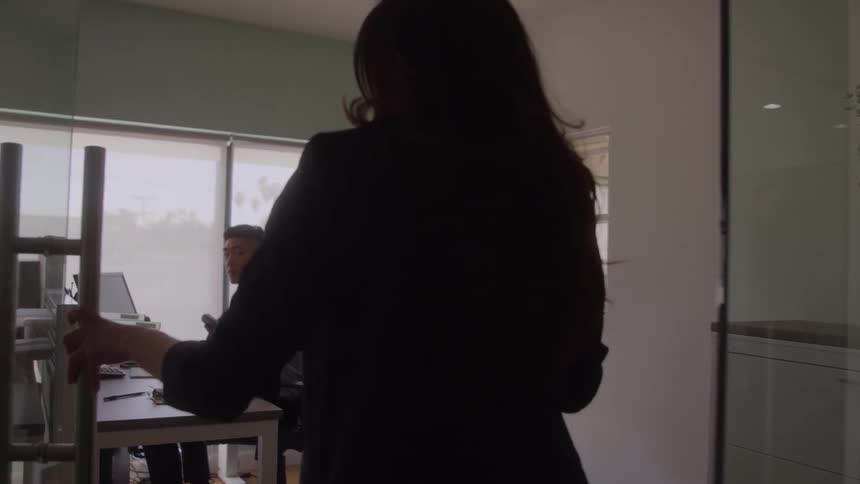 Woman hands a coffee cup to a colleague in a bright office