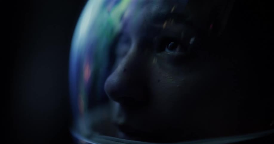 CLose up of an astronauts face with colored reflections in the helmet's visor