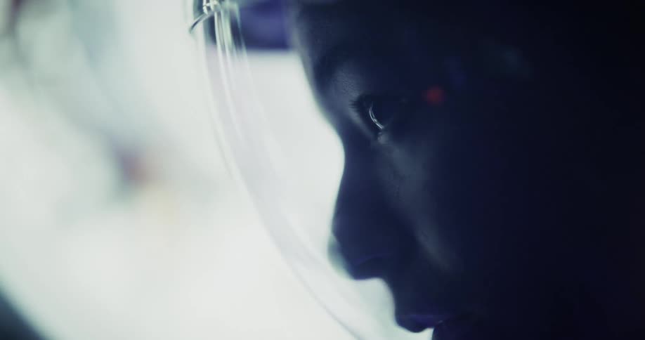 Astronaut carefully observes through the illuminated helmet visor