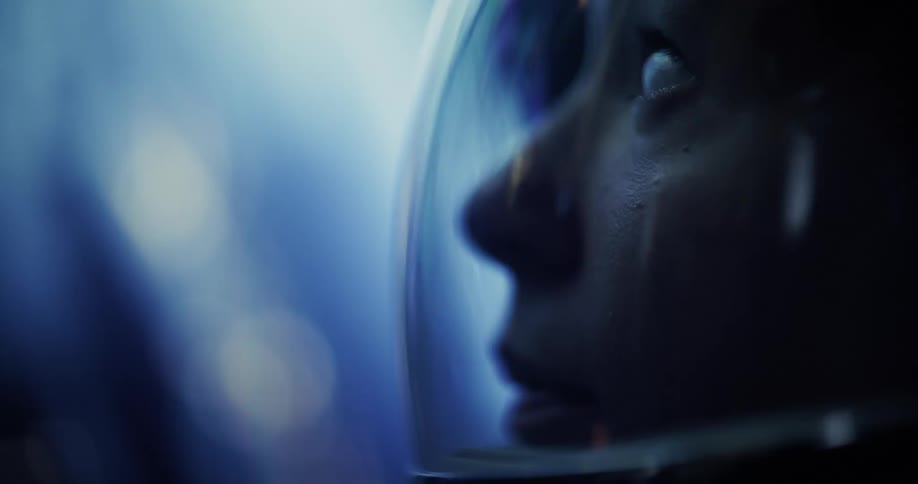 Face inside a space helmet is illuminated by soft blue light
