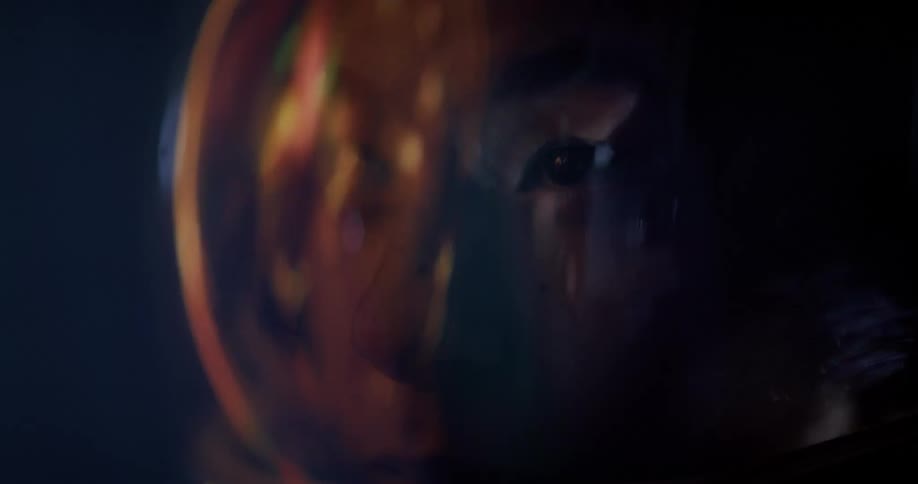 Golden reflection reveals a persons face inside a helmet under bright light