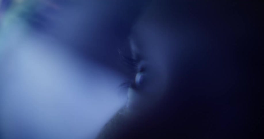 An extreme close up of eyes with colored light reflecting in the foreground