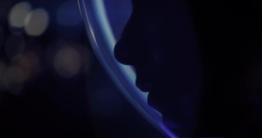 Shadowed profile of a person wearing a helmet lit by soft blue light