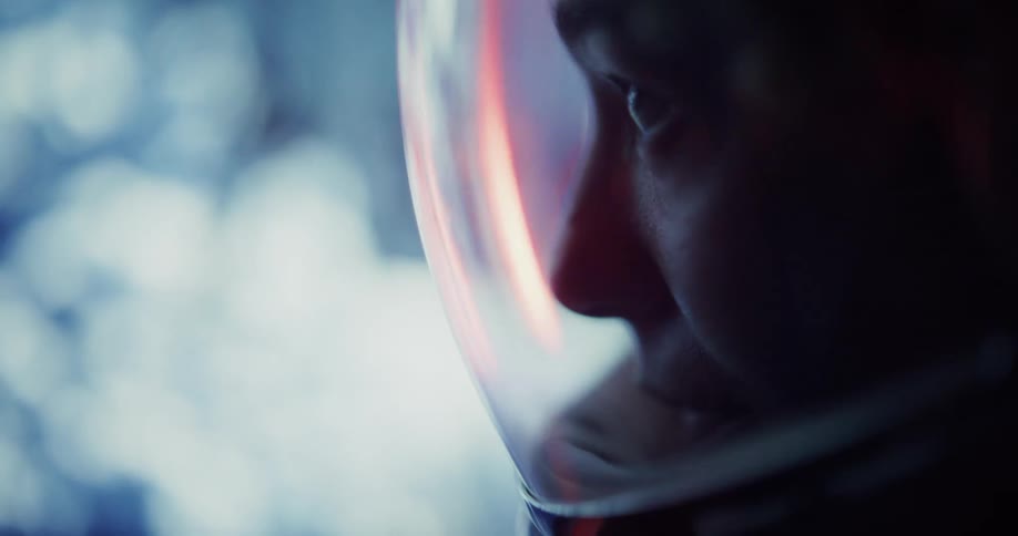 Focused gaze of a person inside a space helmet under bluish light