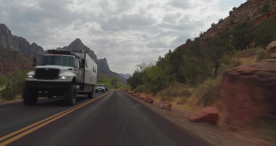 Cars travel along a road surrounded by mountains and dry vegetation