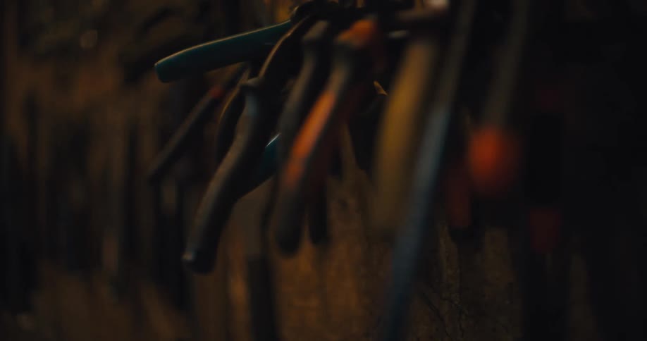 Pliers hanging on a workshop wall under warm lighting