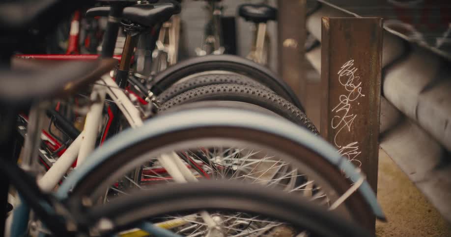 Rows of parked bicycles near a metal structure with graffiti