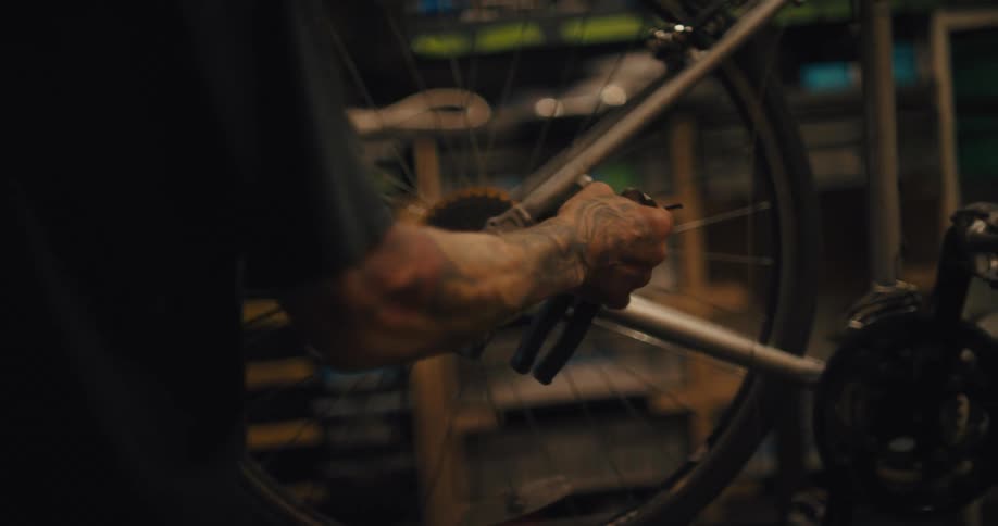 Close up shot of a mechanic working on a bicycle wheel and cassette derailleur in a workshop