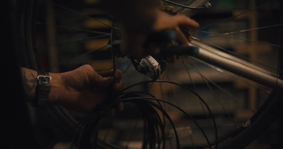 Mechanic adjusts the gear and cables of a bicycle in a workshop