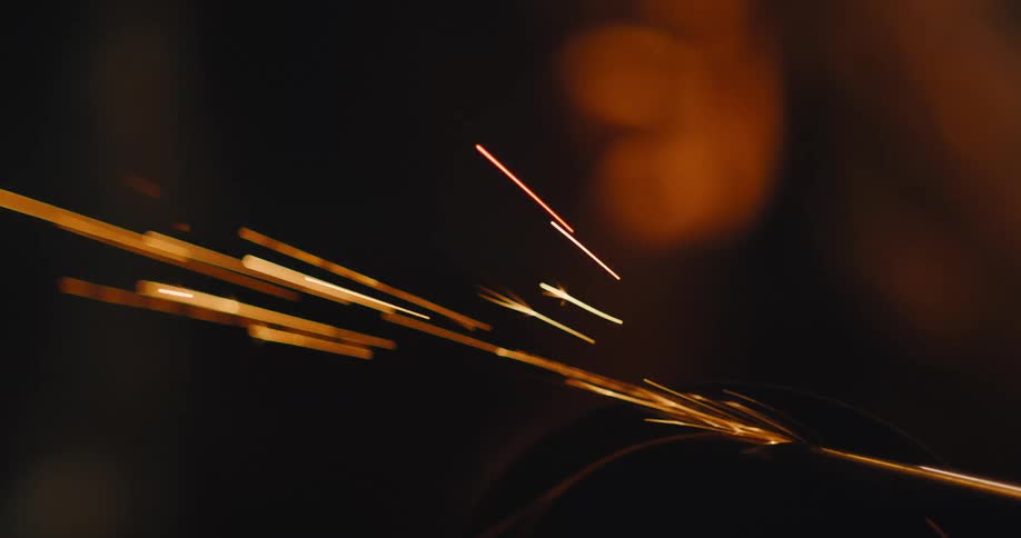Golden sparks fly from a tool in operation in the dark