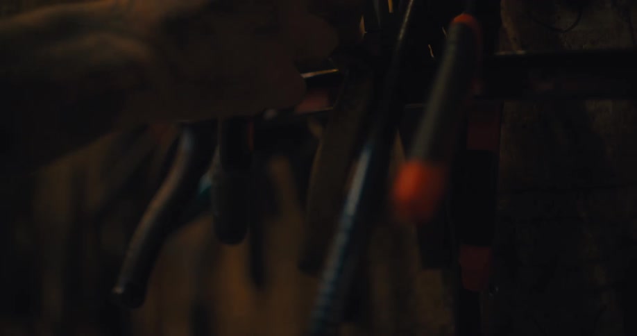 Hands replace tools on a rack in a workshop