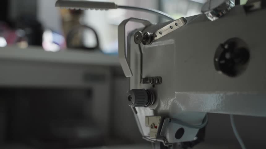 Industrial sewing machine in use with fabric being guided by hands