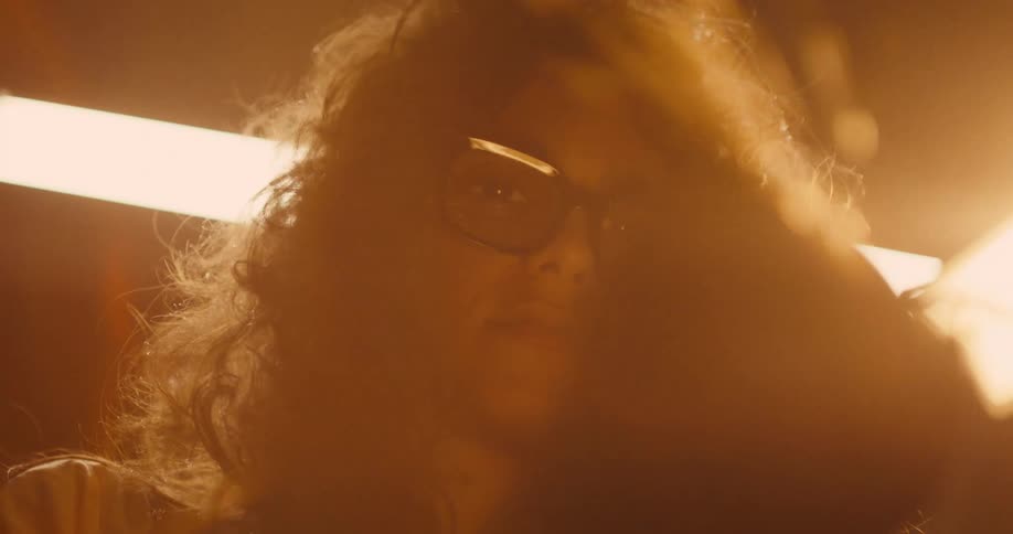 Slow motion shot of a woman  wearing protective glasses, using an angle grinder sending sparks into the air