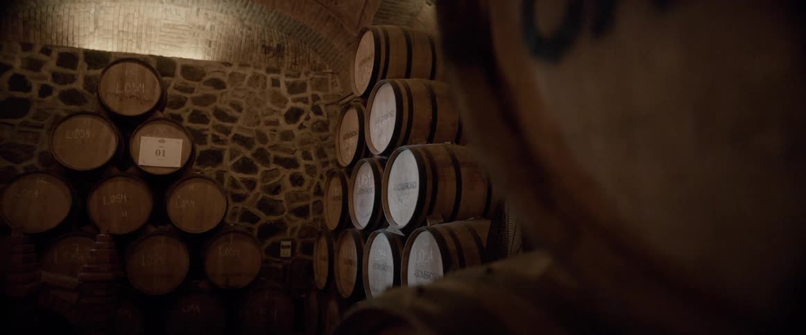 Wine barrels are stacked in a pyramid shape in a storage room