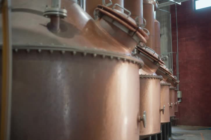 Copper tank with pressure gauge releasing steam in a rustic masonry setting
