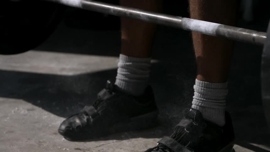 A man drops a barbell with weights onto the ground while exercising