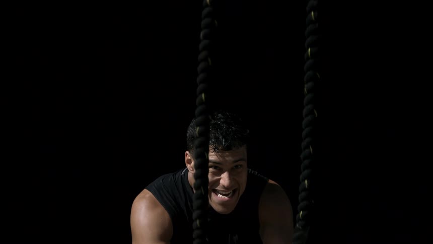 A man is exercising with battle ropes