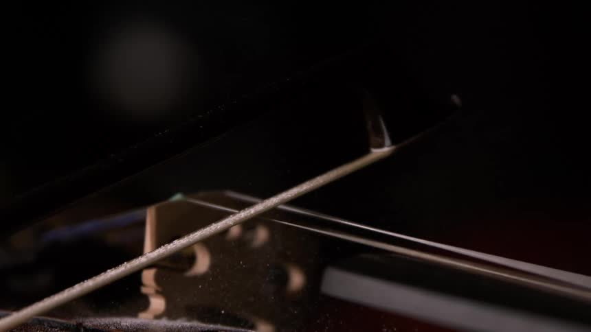 A bow is slowly moved across the string of a violin