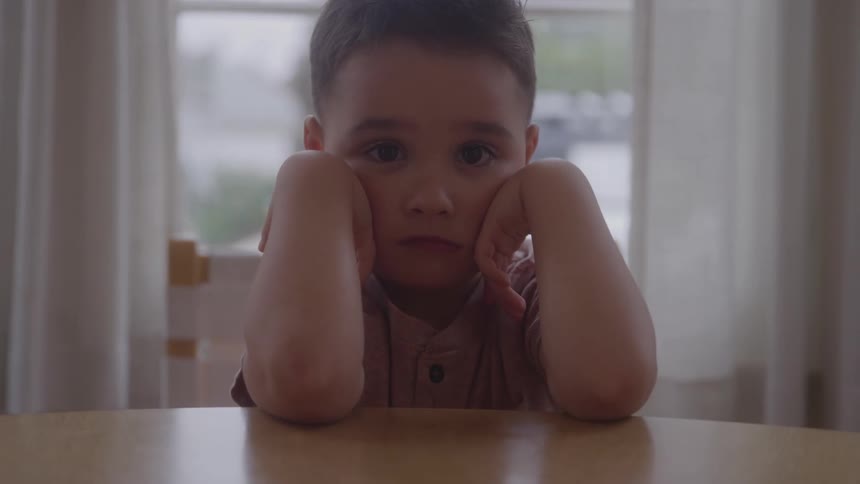 Toddler pouting with his elbows on the table