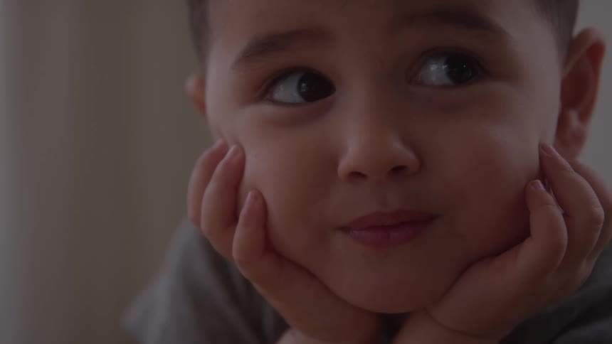 The child leans his head on his hands