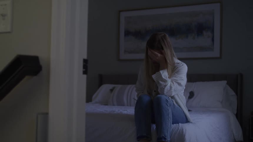 The woman is crying in the bedroom