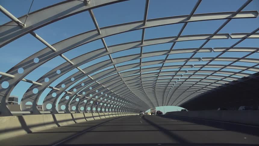 View of a road with cars and a metal rail above