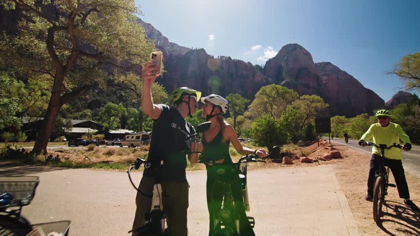 Two cyclists take a selfie while kissing during a cycling outing near the mountains on a sunny autumn day
