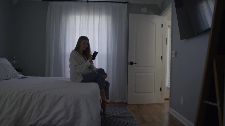 Woman sitting on the bed talking on the phone in a bright room
