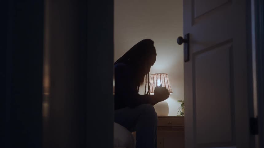 The woman looks sad as she sits on the bed