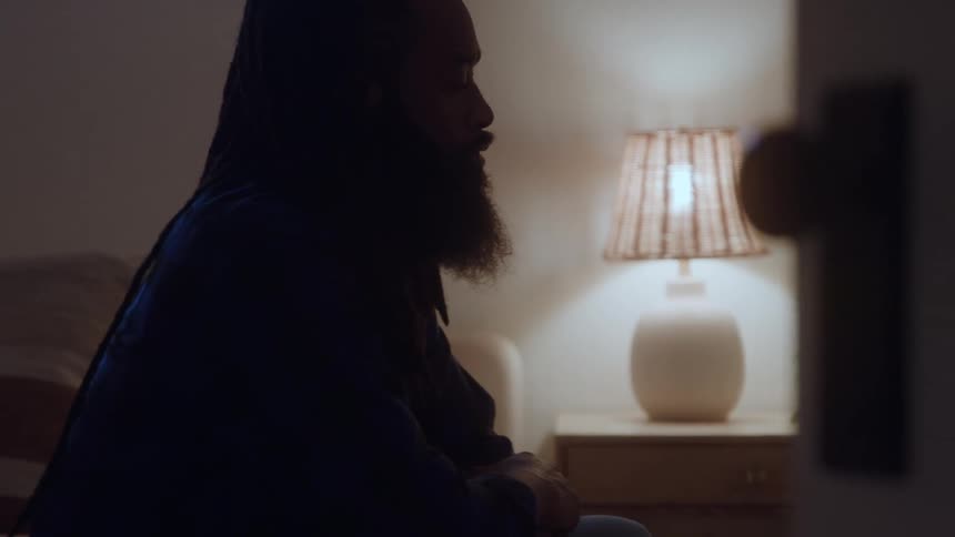 Man sits in silence reflecting under the soft light of a lamp