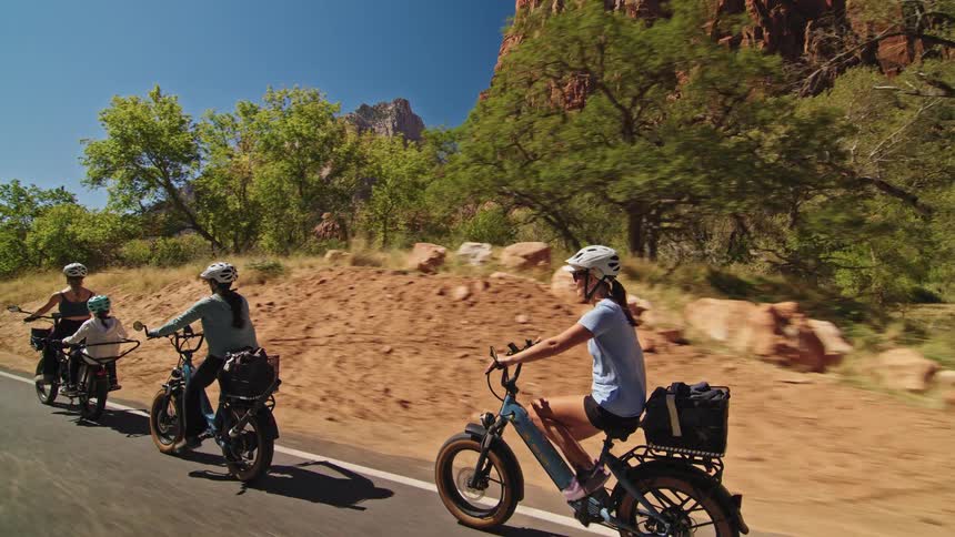 A group of people bike along a road