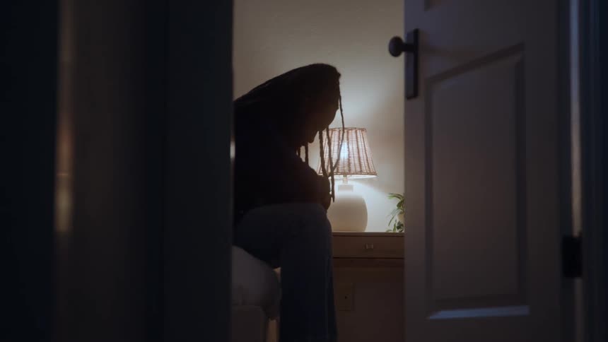 A woman sadly sits on the bed