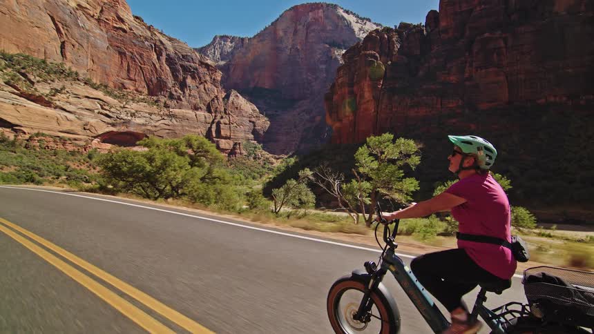 A woman bikes along a canyon road