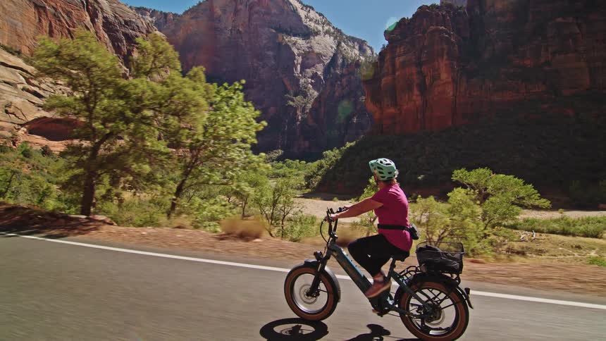 Cyclist rides along a road surrounded by canyons under a deep blue sky