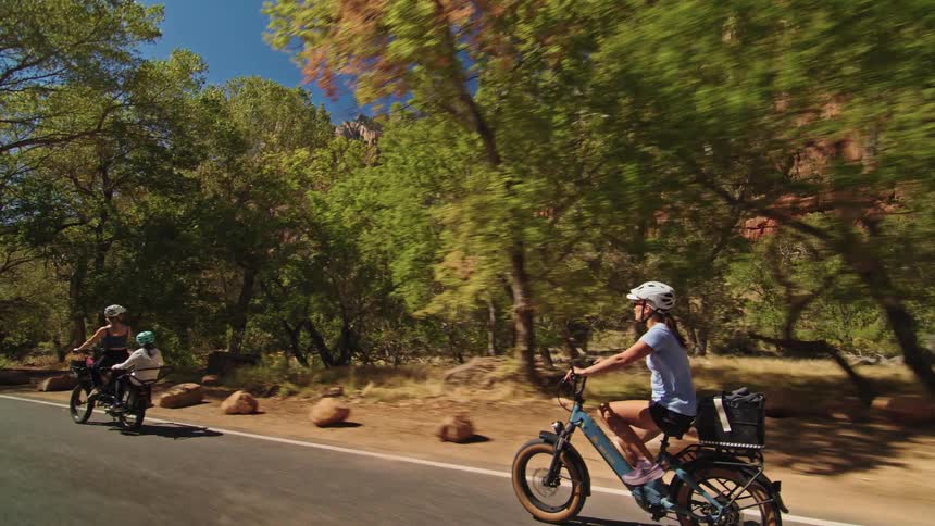 People riding bicycles on a road with mountains in the distance