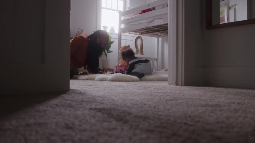 The father is playing with his daughter in the bedroom