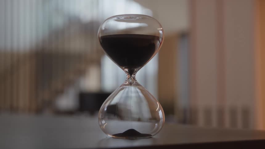 Sand falls inside an hourglass on a table