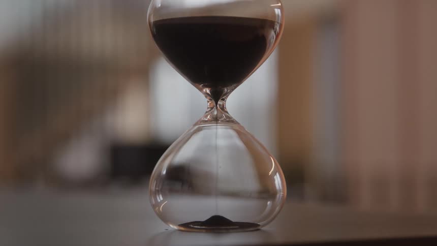 Sand falls inside an hourglass on a table
