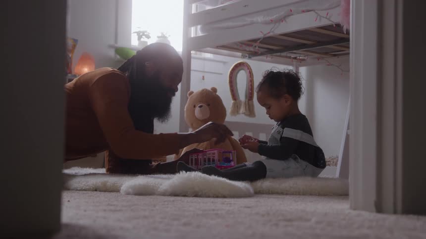 The father and daughter play together on the floor